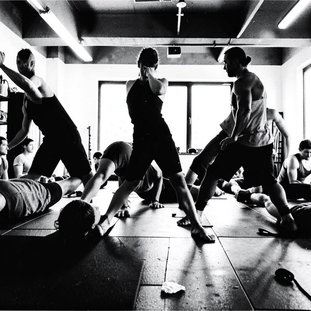 A group of people performing fitness exercises together in a bright studio, warm duotone with amber and deep charcoal tones